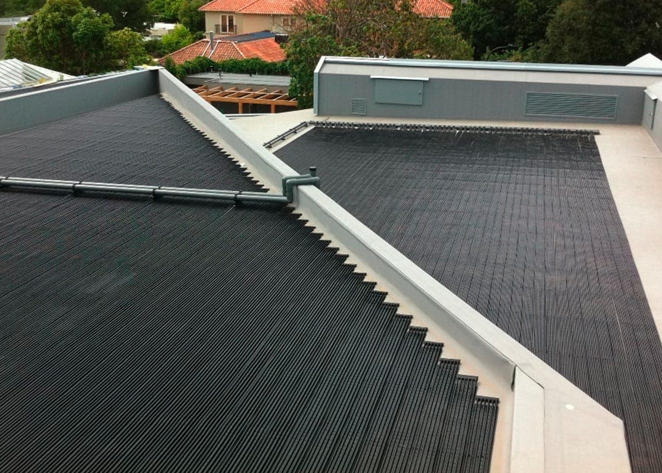 Flexible strip solar pool heating covering two flat roof sections